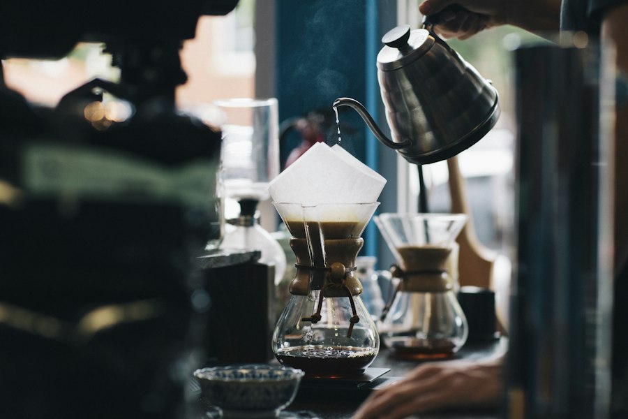 A kettle pouring into a pour-over brewer by a window